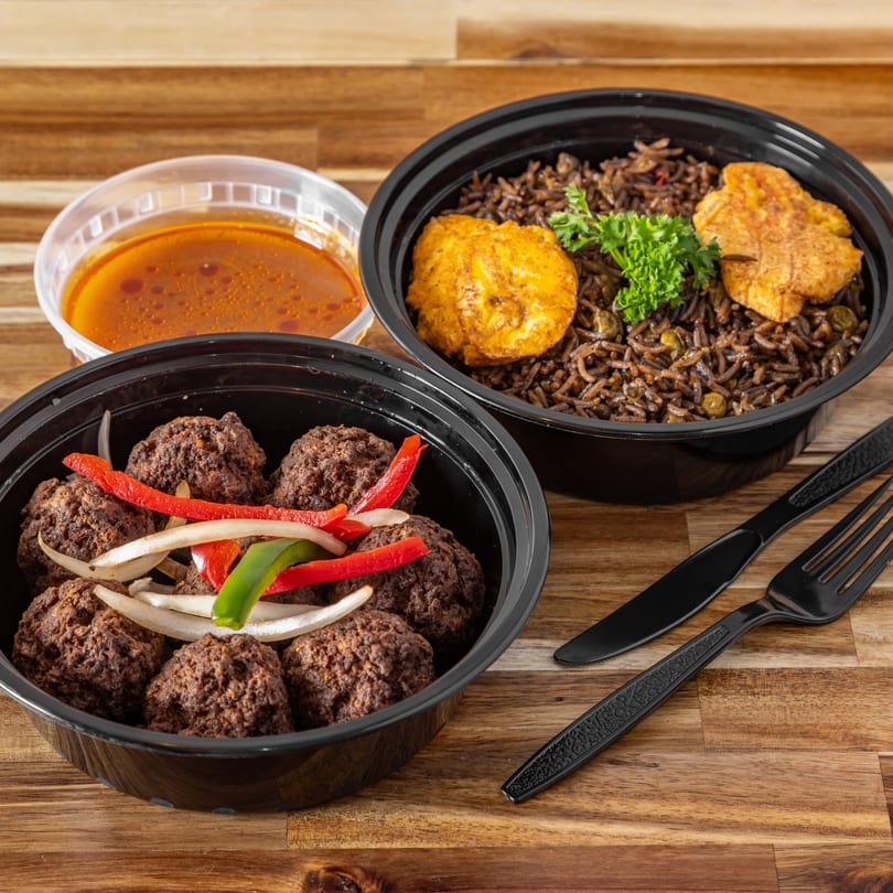 Two Haitian takeout containers with meatballs, rice, plantains, and a side of sauce.