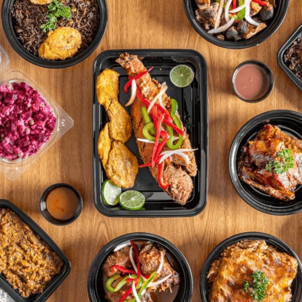 A top-down view of a variety of Caribbean dishes, including fried fish, rice, and meat.