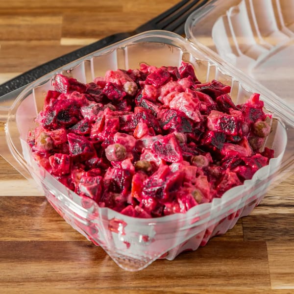 Vinaigrette salad with beets, potatoes, carrots, pickles, and peas in a clear plastic container.